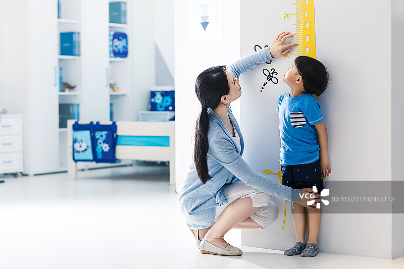 妈妈在为小男孩测量身高图片素材