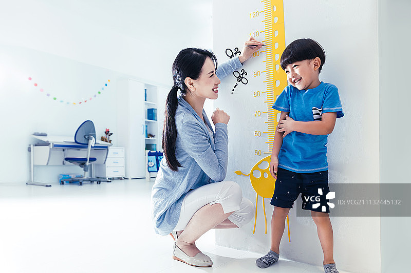 妈妈在为小男孩测量身高图片素材