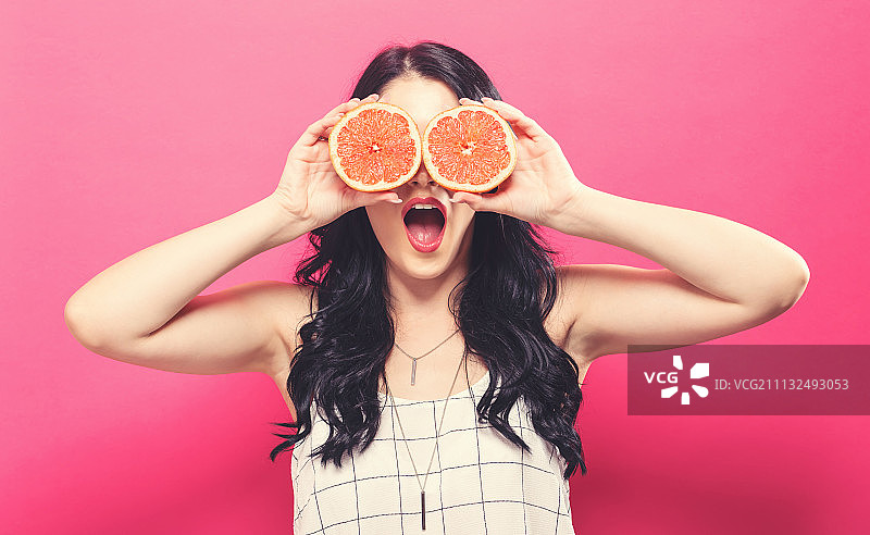 手拿橙子的快乐年轻女人图片素材