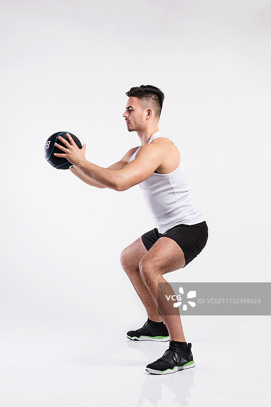 英俊的健身男人拿着药球，工作室拍摄。图片素材