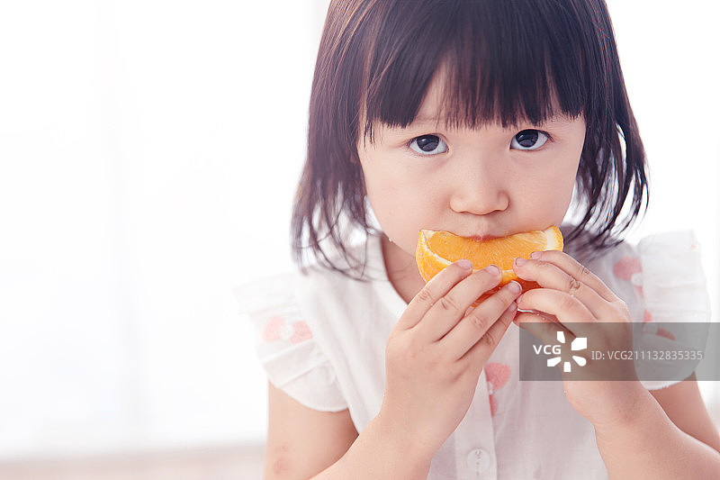 可爱的小女孩在吃橙子图片素材