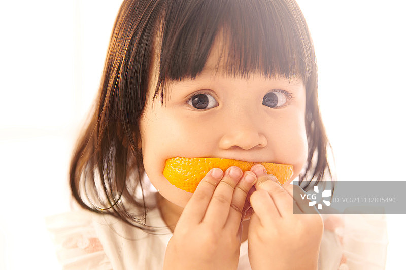 可爱的小女孩在吃橙子图片素材