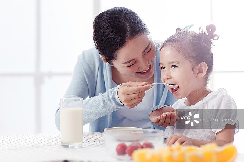 母亲在喂女孩吃饭图片素材