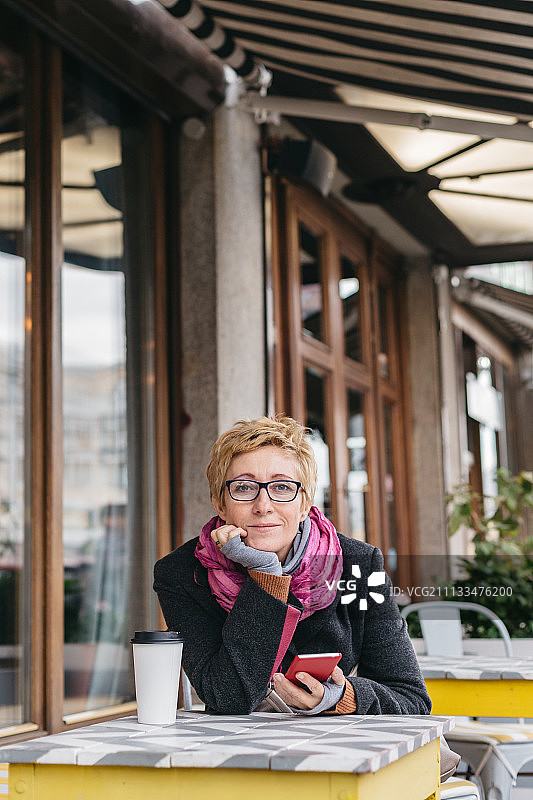 在咖啡馆里拿着手机的梦幻女人图片素材