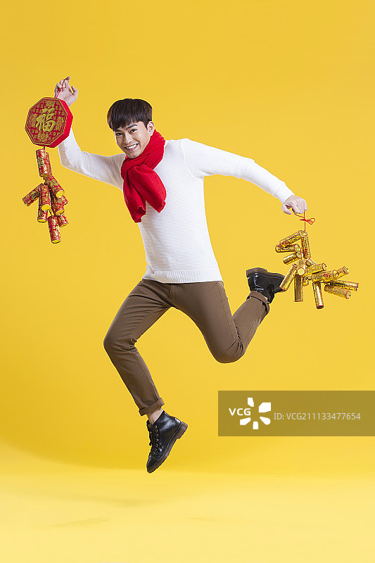 快乐的年轻男子拎着鞭炮庆祝新年图片素材