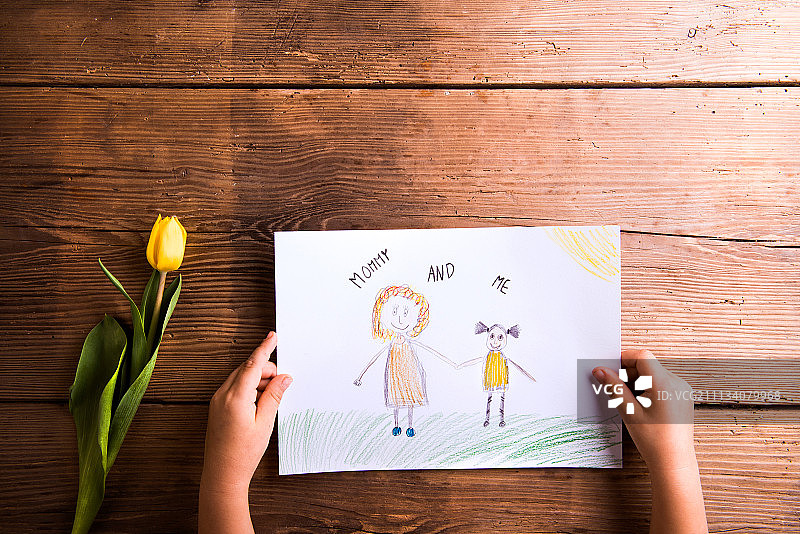 女孩手拿妈妈画作和黄色郁金香影棚拍摄图片素材