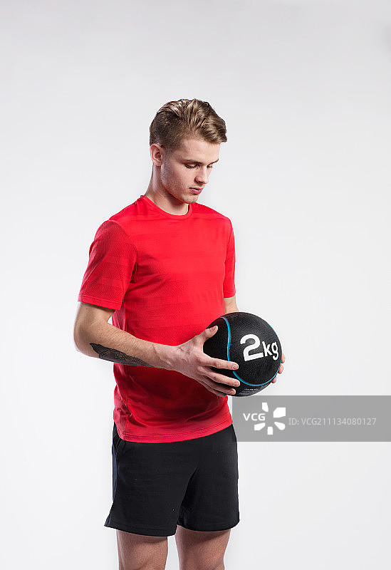 英俊的健身男人拿着药球，工作室拍摄。图片素材