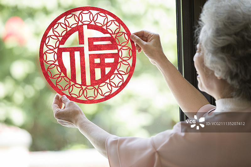 快乐的老年女子贴新年窗花图片素材