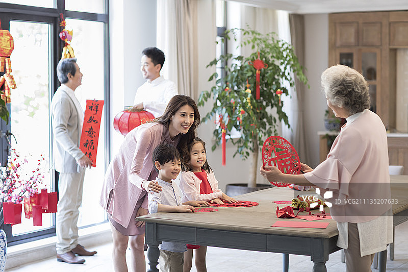 快乐的奶奶教孙子们剪新年窗花图片素材