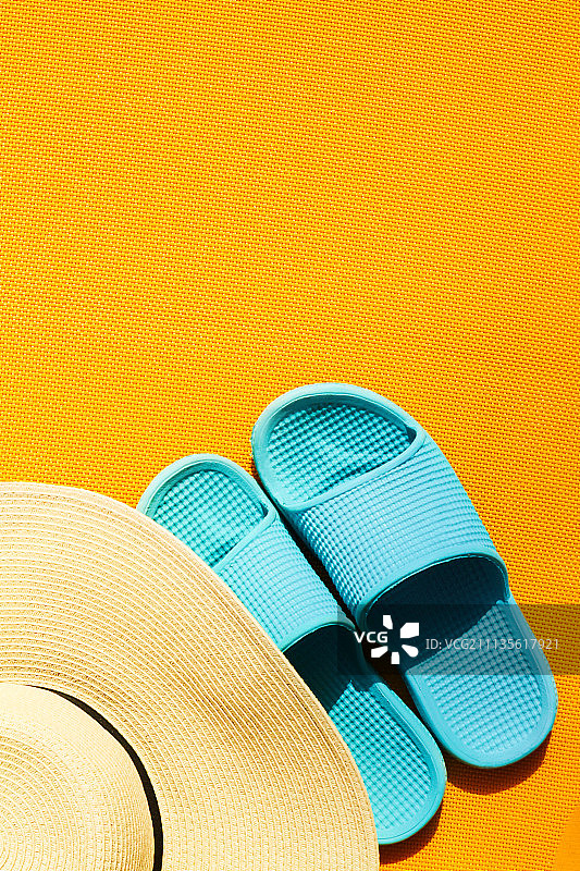 黄色背景上的蓝色人字拖与美丽草帽图片素材