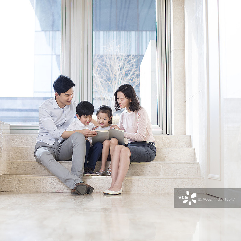 快乐的年轻家庭在客厅看书图片素材