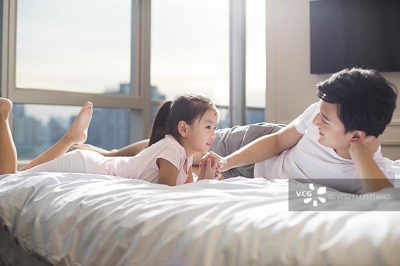 快乐年轻父女在床上玩耍图片素材