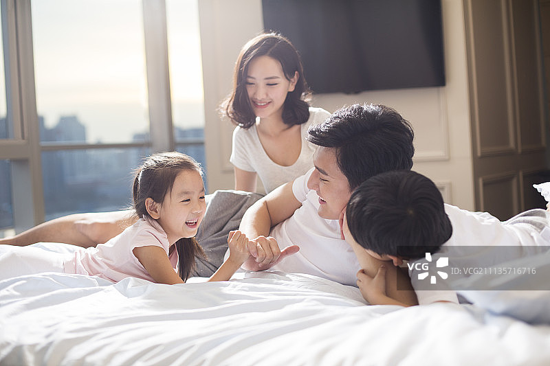 快乐年轻家庭在床上嬉戏图片素材