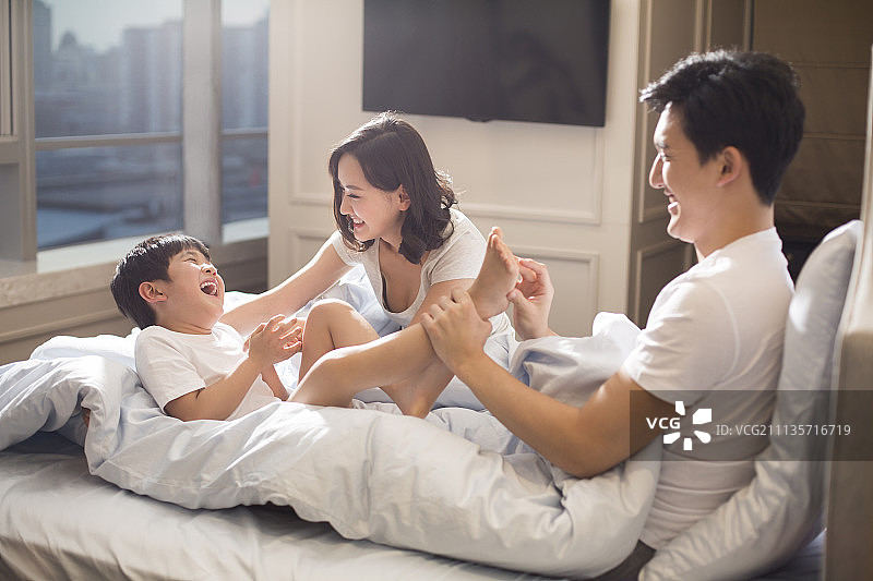 快乐年轻家庭在床上嬉戏图片素材