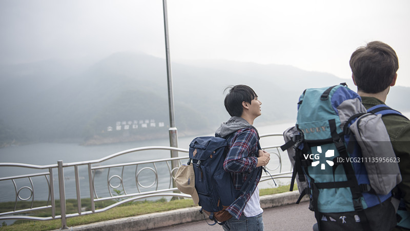 两名背包客在春川市昭阳湖和山脉的道路上行走图片素材