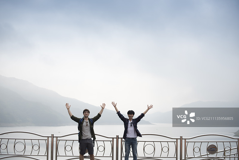 朋友们一起旅行玩耍，两人在昭阳湖畔举起双臂图片素材