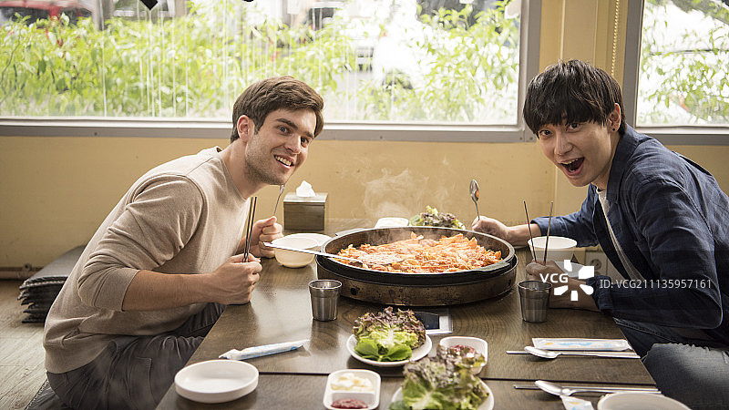 朋友们一起旅行，两个朋友在餐厅吃韩国料理图片素材