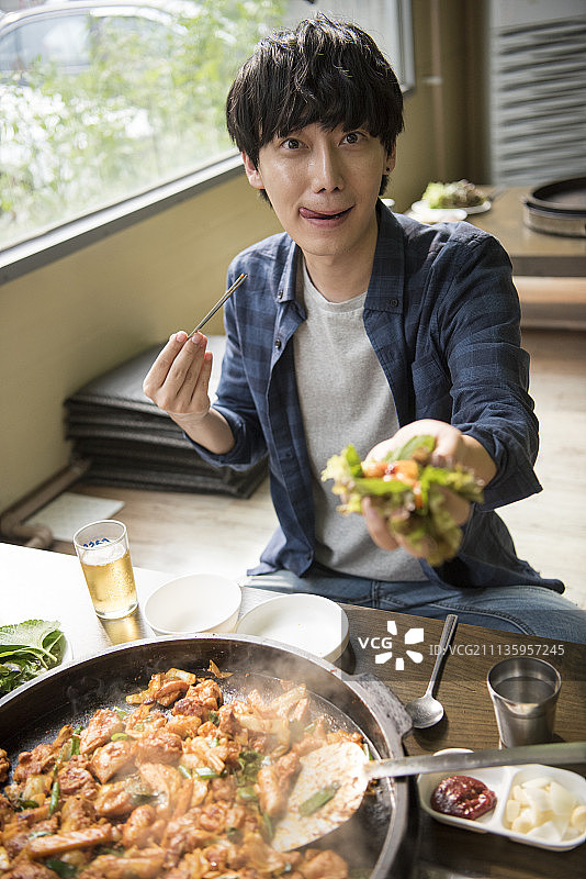 在餐厅拿着韩国食物的微笑男人图片素材