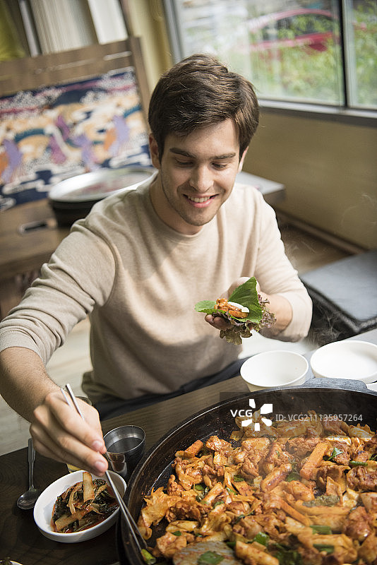 青年男子在餐厅享用韩国料理和啤酒图片素材