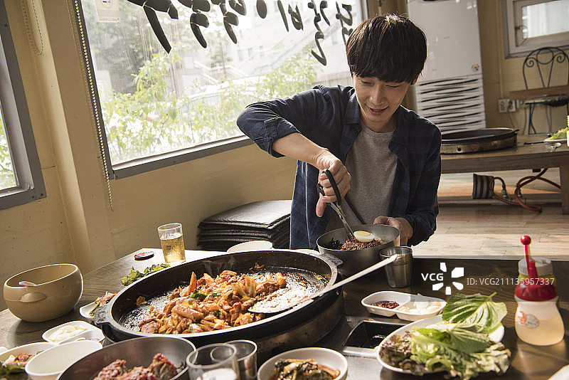 在餐厅用筷子享用韩国料理的年轻男人图片素材