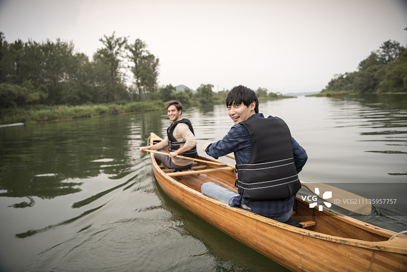 朋友们旅行，两个男人穿着救生衣在昭阳湖上划独木舟图片素材