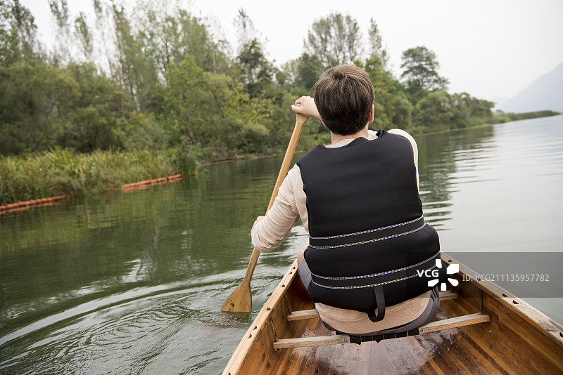 穿救生衣在昭阳湖群山间划独木舟的男人图片素材
