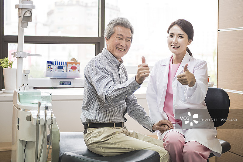 女牙医和老年患者在诊所对着镜头竖起大拇指微笑图片素材