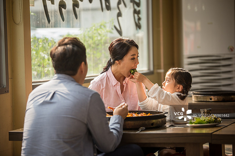 幸福家庭在韩国餐厅用餐，孩子喂妈妈图片素材