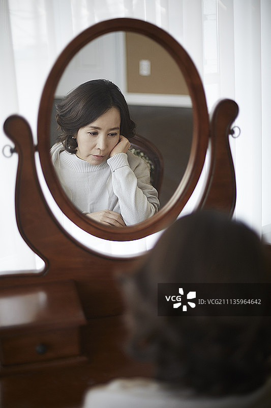卧室里坐在镜子旁表情沮丧的女人照片图片素材
