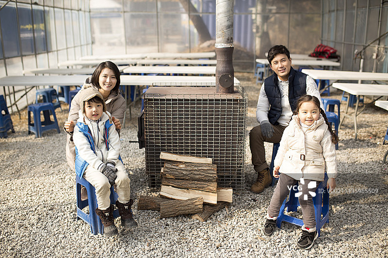 一家人坐在取暖器和木柴旁边的摄影图片素材