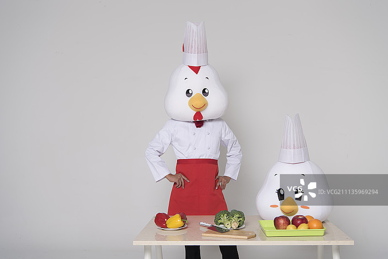 厨师拿着鸡头站在桌子旁的影棚照图片素材