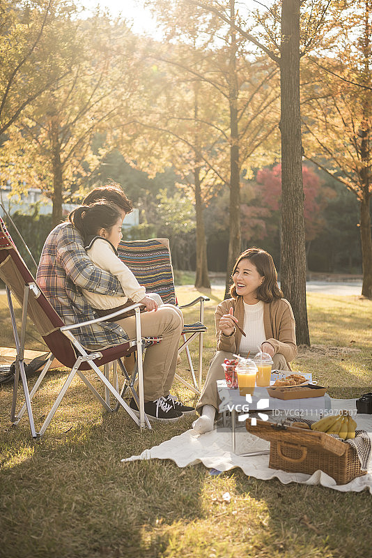 秋季公园里坐在躺椅上野餐，母亲喂女儿图片素材