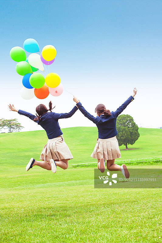 拿着气球跳跃的高中女生图片素材