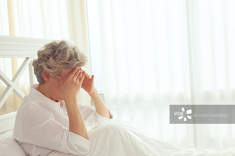 坐在床上的70岁老妇人图片素材