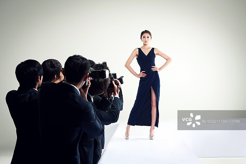 在T台上摆姿势的女人和摄影记者图片素材