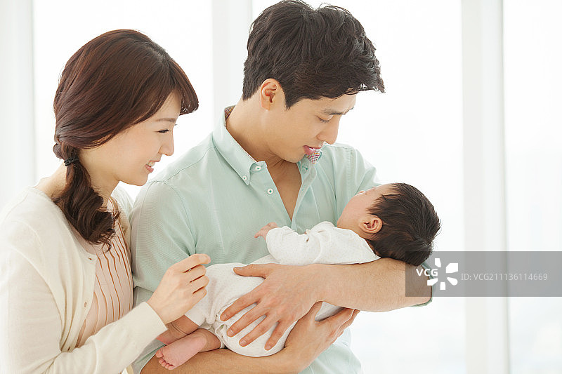 夫妇在厨房做饭，抱着婴儿，双职工家庭图片素材