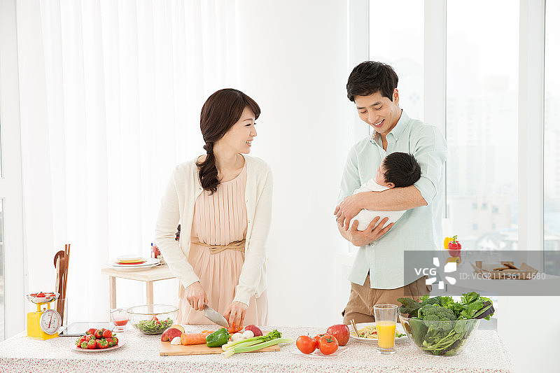 夫妇在厨房做饭，抱着婴儿，双职工家庭图片素材