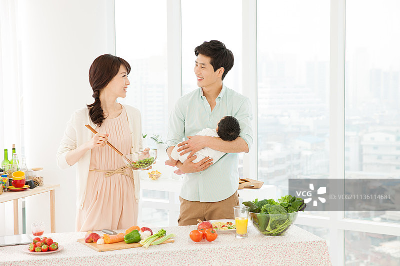 夫妇在厨房做饭，抱着婴儿，双职工家庭图片素材