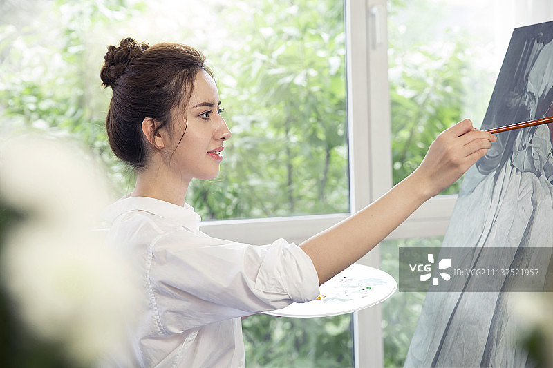 年轻女子在画室画画图片素材