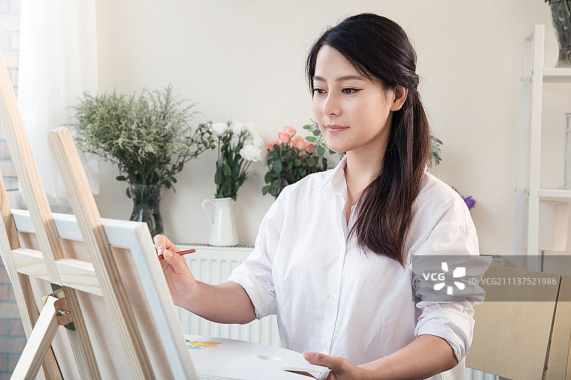 年轻女子在工作室画画图片素材