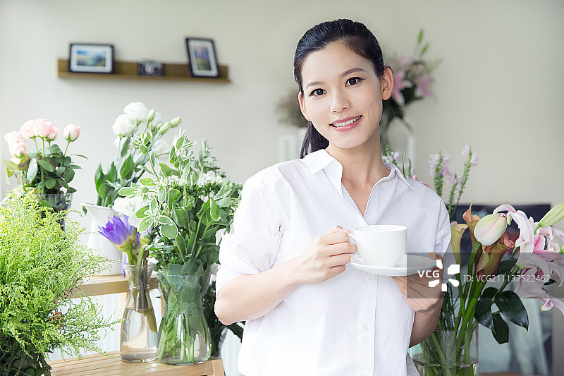 年轻女子喝咖啡在插花工作室图片素材