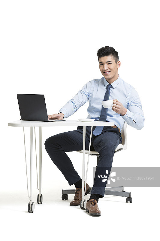 在办公室喝咖啡的年轻商务男士使用电脑图片素材
