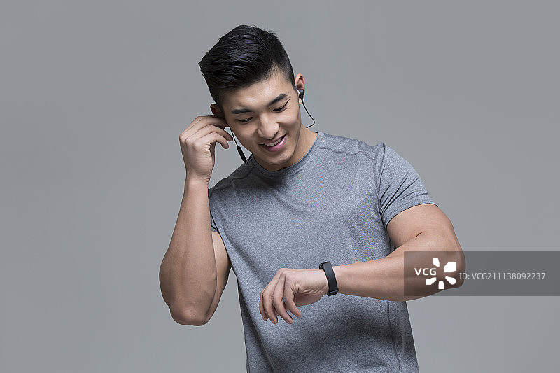 戴耳机的男运动员运动后查看智能手环图片素材