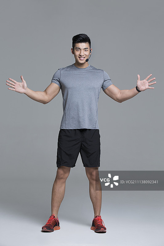 佩戴耳麦的快乐男教练在健身房授课图片素材