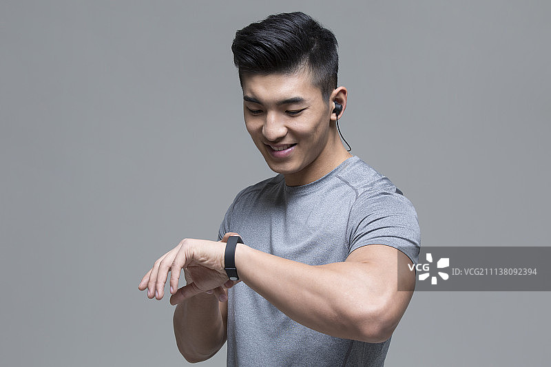 戴耳机的男运动员运动后查看智能手环图片素材