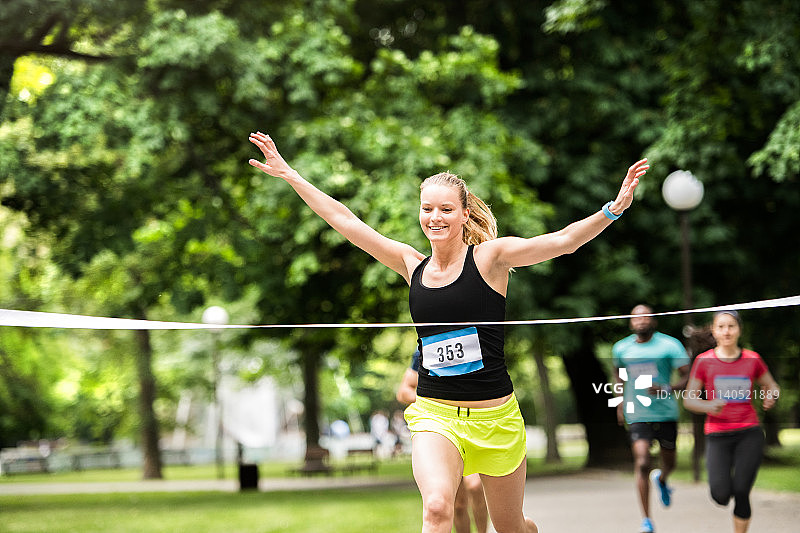 在人群中冲过终点线的年轻女人图片素材