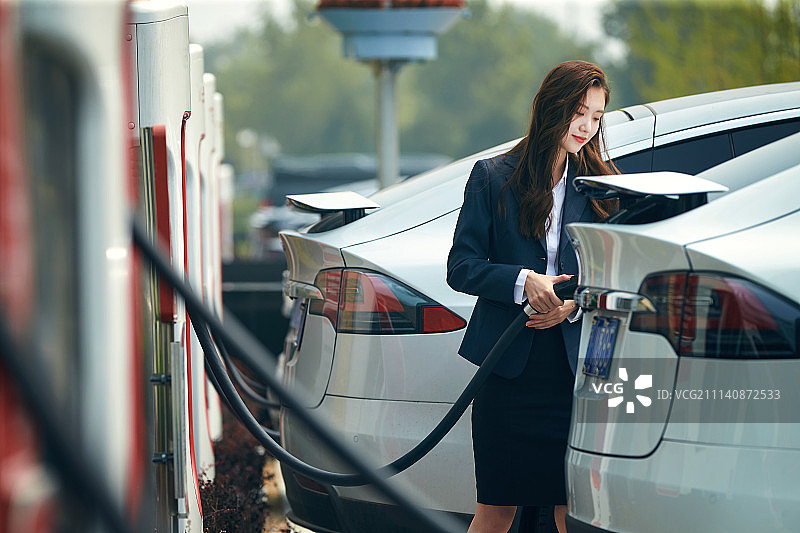 青年女人给电动汽车充电图片素材