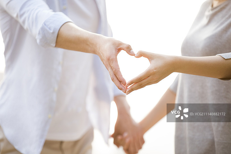 快乐的年轻情侣摆心型手势图片素材