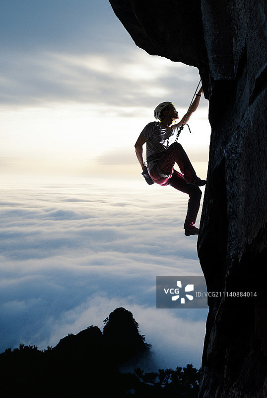 中年男人悬崖上攀岩图片素材