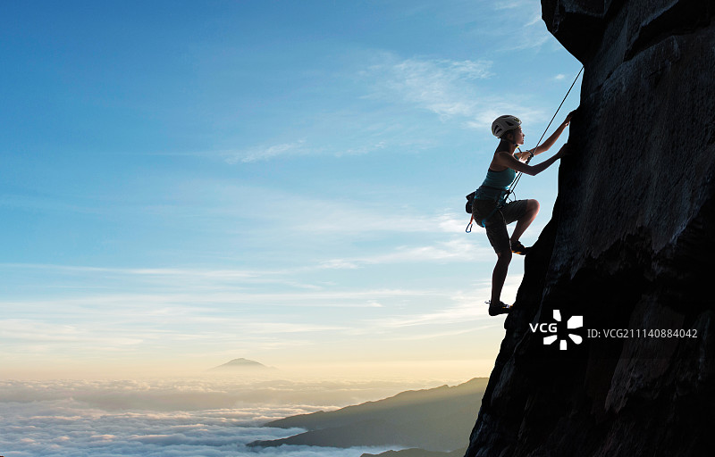 青年女人悬崖上攀岩图片素材